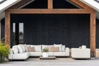 White outdoor sofa set on a patio with wooden pergola and black wall background