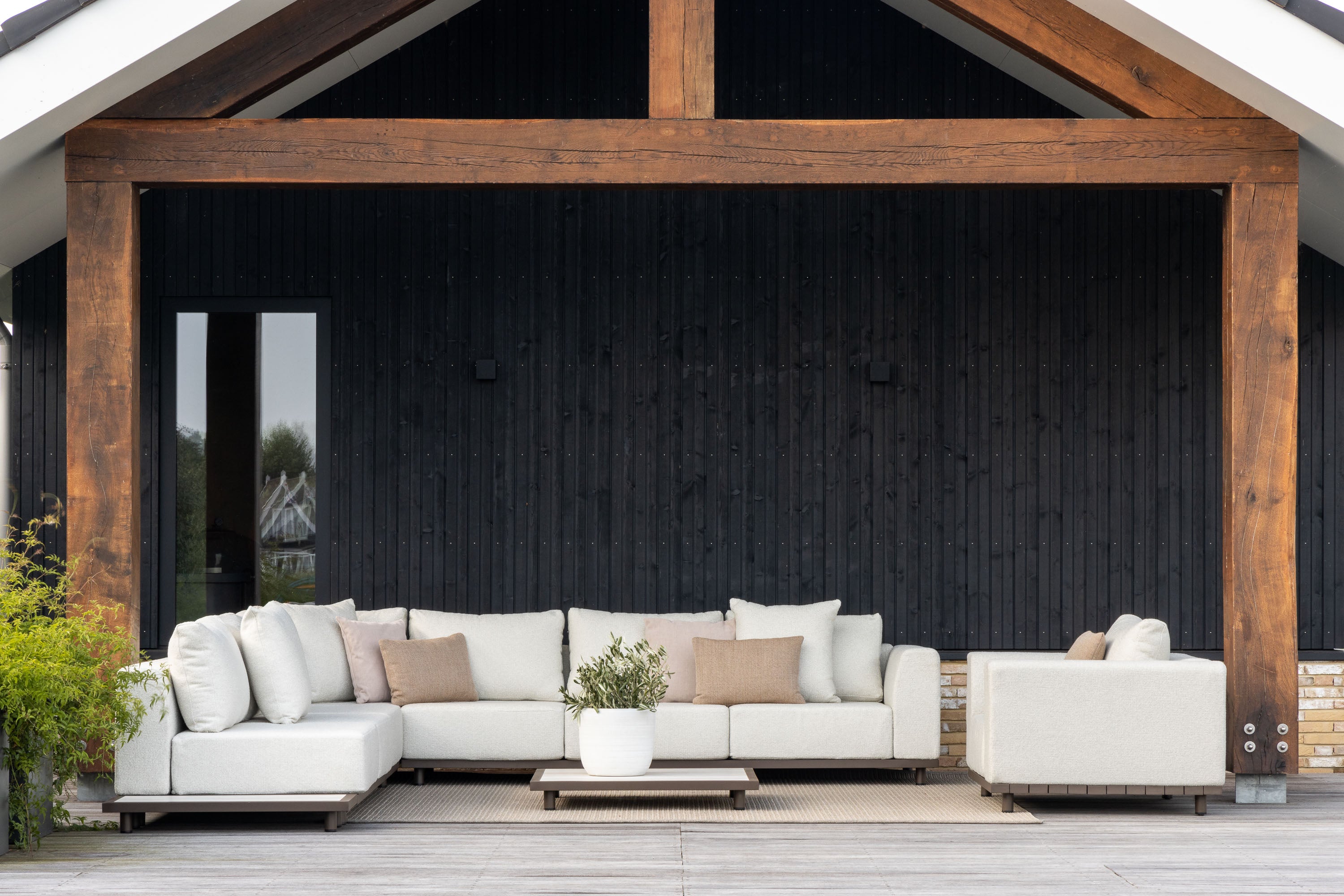 White outdoor sofa set on a patio with wooden pergola and black wall background