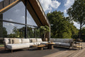 Outdoor patio with modern furniture set against a backdrop of trees and a clear sky.