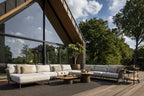Outdoor patio with modern furniture set against a backdrop of trees and a clear sky.
