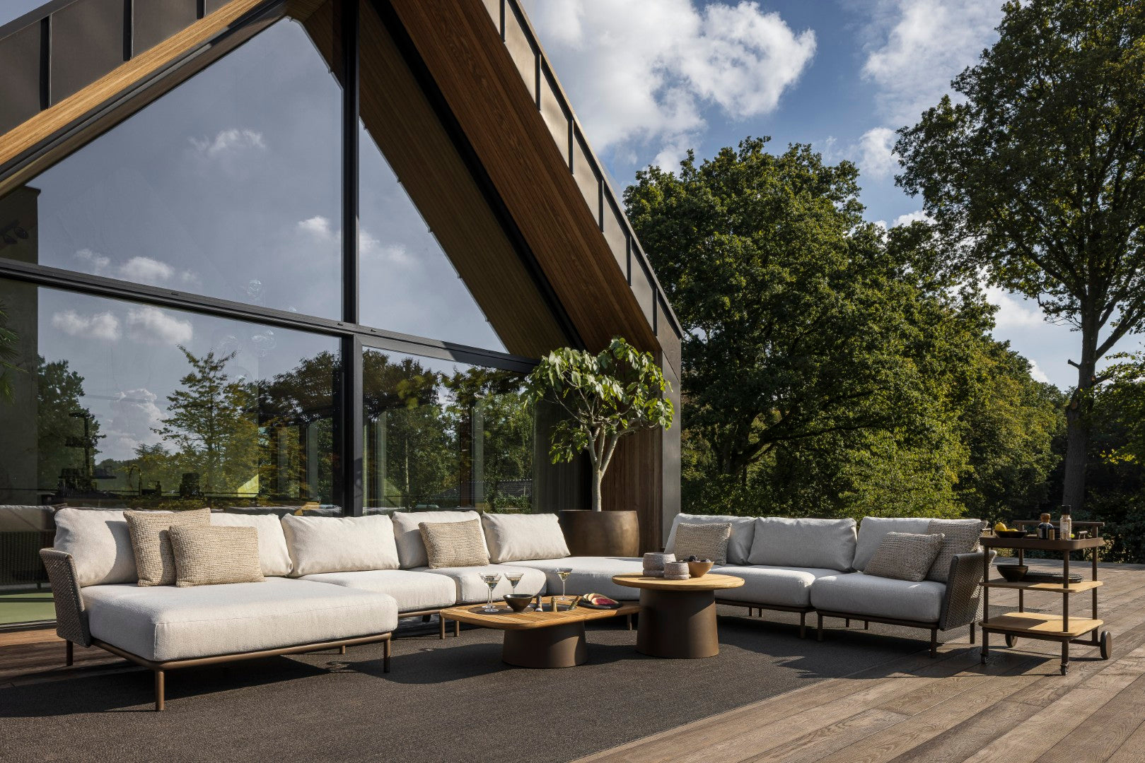 Outdoor patio with modern furniture set against a backdrop of trees and a clear sky.