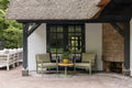 A cozy outdoor seating area features two olive-green casual dining chairs with cushioned seats, positioned around a round wooden side table.