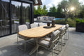 Outdoor patio setting with a wooden dining table and chairs on a stone patio.