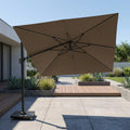 Brown patio umbrella on a stand in an outdoor setting with a house and garden in the background.